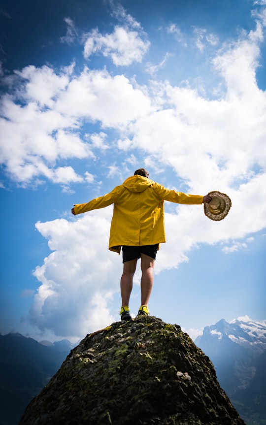 man holding brown strawhat standing on top of rock in Grindelwald Switzerland