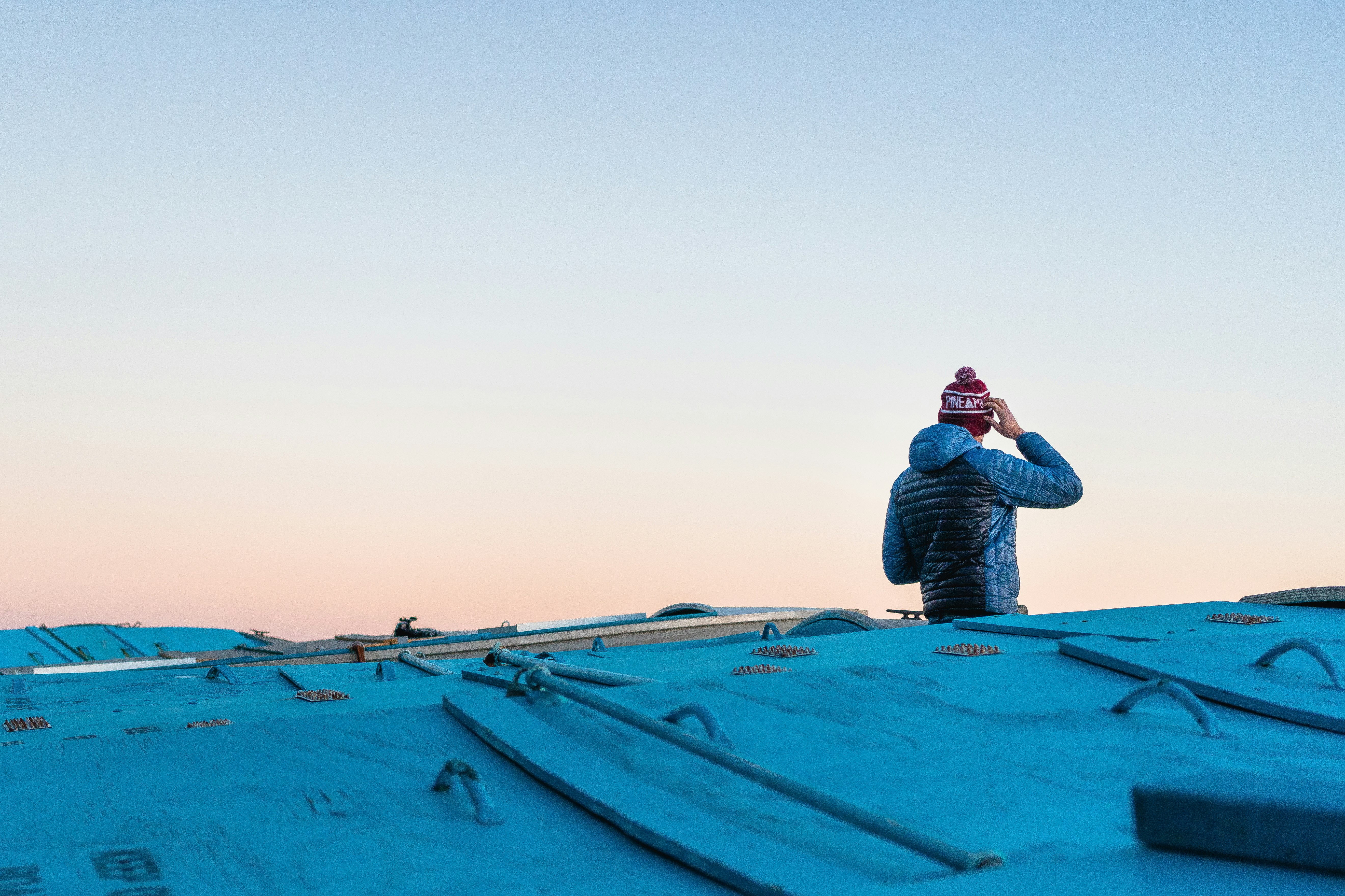 man scratching head on roof top under white sky