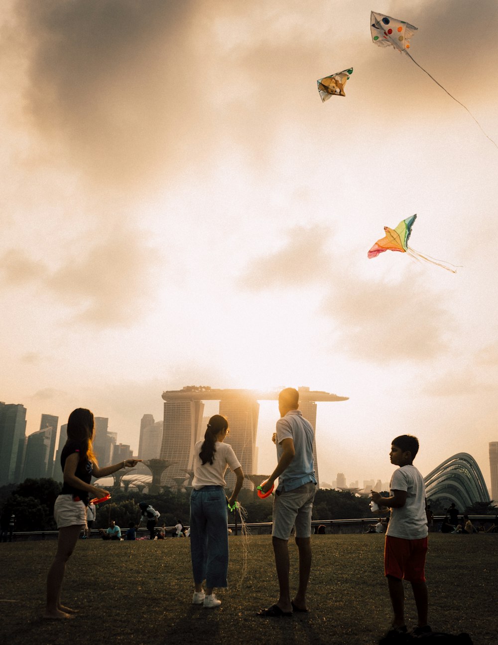 four person playing kite on grass field