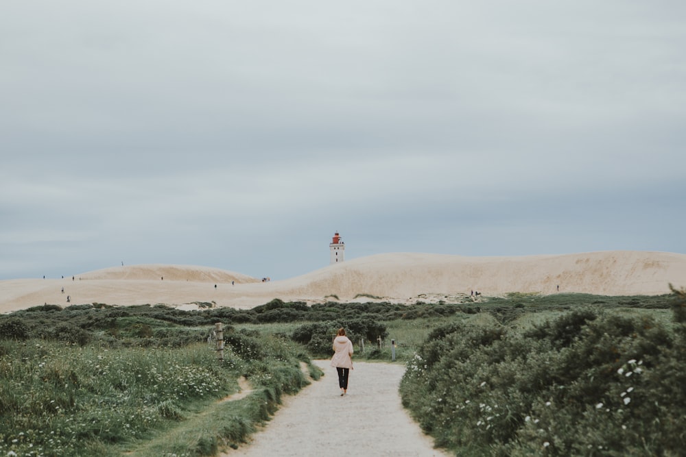 woman walking beside green grasses during daytime