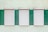 Three closed window shutters are aligned in a row on a textured wall. The wall is painted in alternating vertical green and light yellow stripes, creating a contrast between the white shutters and the background.