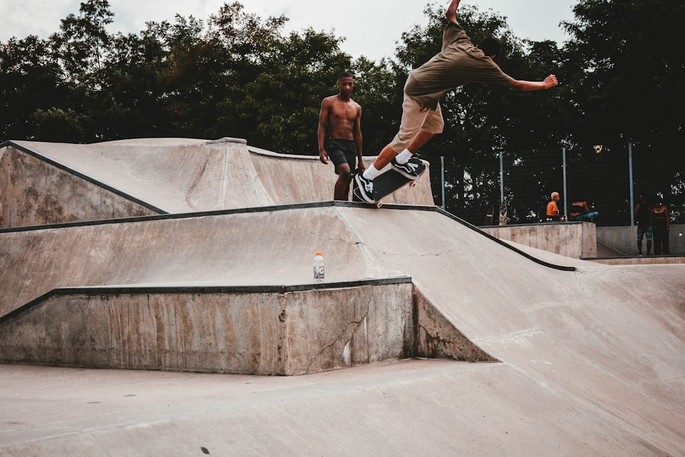 man grinding skateboard on ramp ledge near man