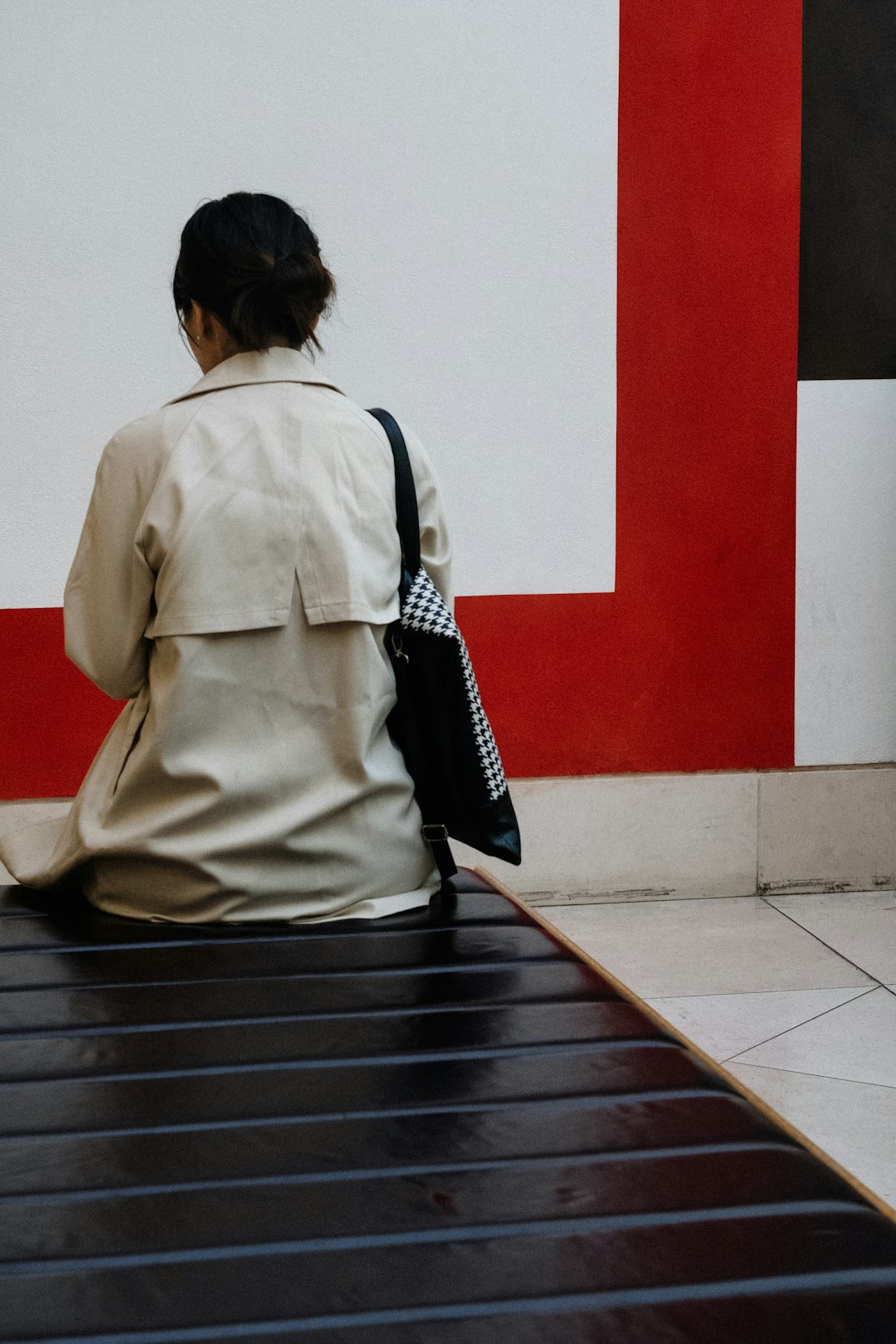 woman sitting fronting white and red wall