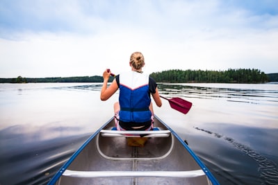 woman holding paddle riding boat on body of water canoe teams background