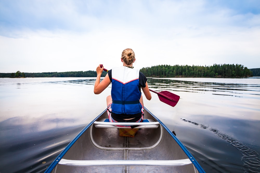 woman holding paddle riding boat on body of water