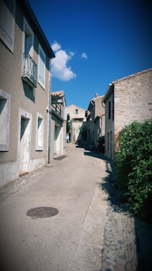 Old village street with whitewashed houses and cobblestones under a clear sky.