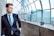 Photo of a confident man in business attire standing by a city skyline.