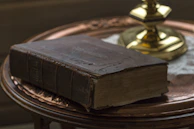 A detailed shot of an old, weathered book of spells resting on a wooden table with natural light.