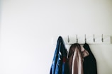 three jacket hanging on wall hooks