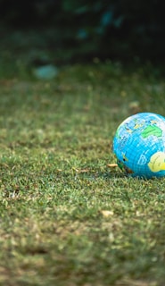 blue and white desk globe on green grass field during daytime