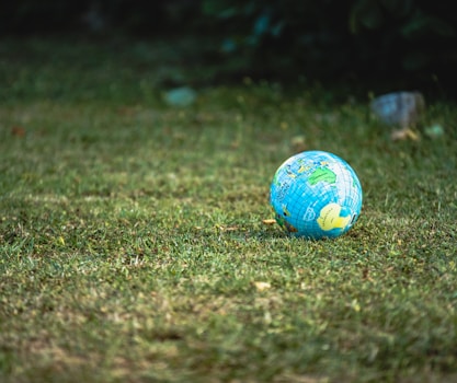 blue and white desk globe on green grass field during daytime