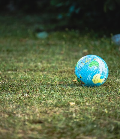 blue and white desk globe on green grass field during daytime