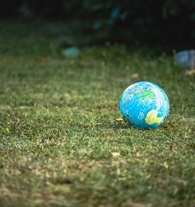 blue and white desk globe on green grass field during daytime