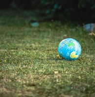 blue and white desk globe on green grass field during daytime