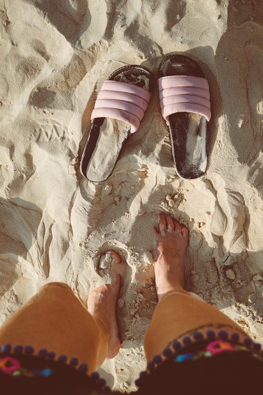 person standing on sand with slide sandals