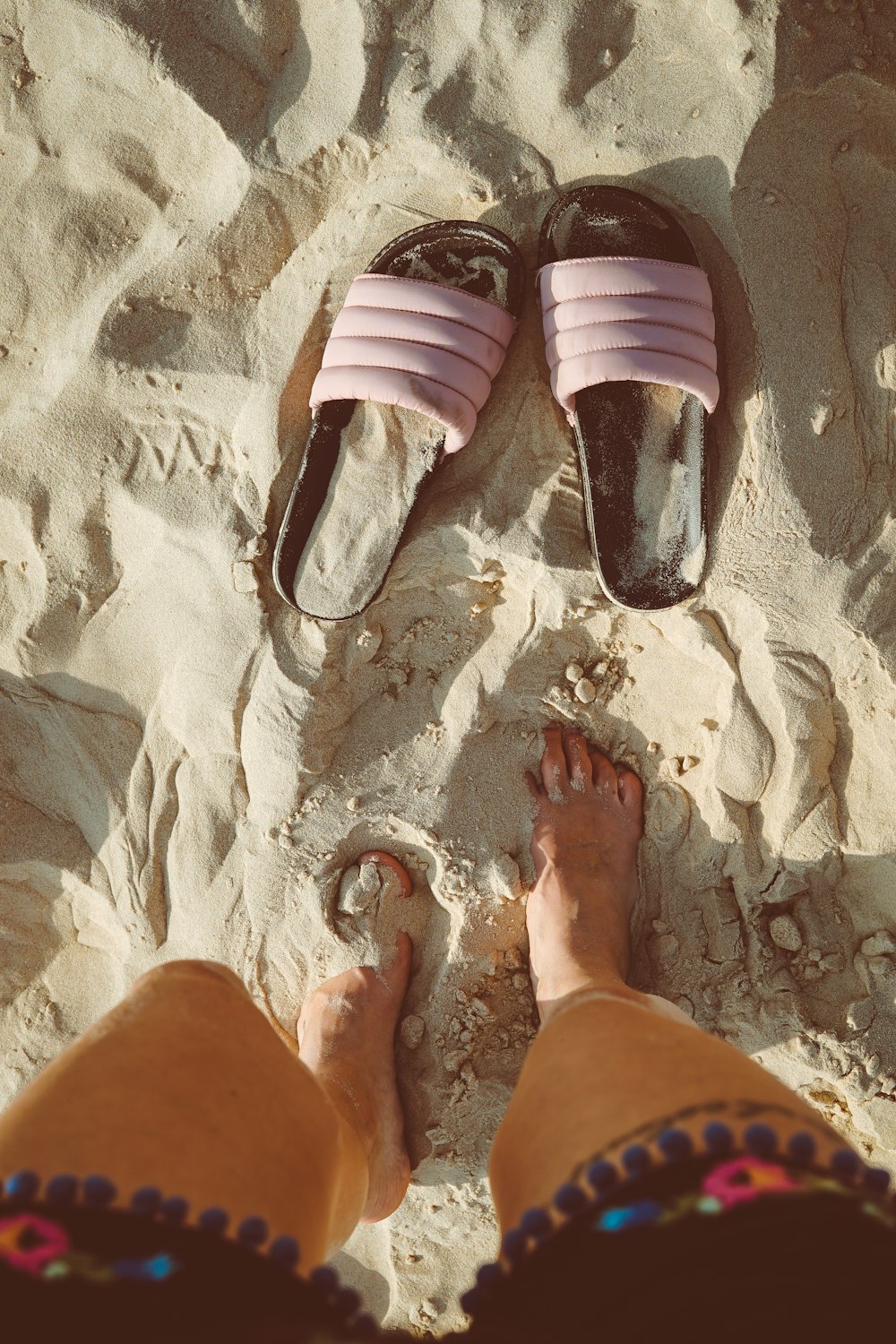 Persona de pie en la arena en sandalias de diapositivas delanteras