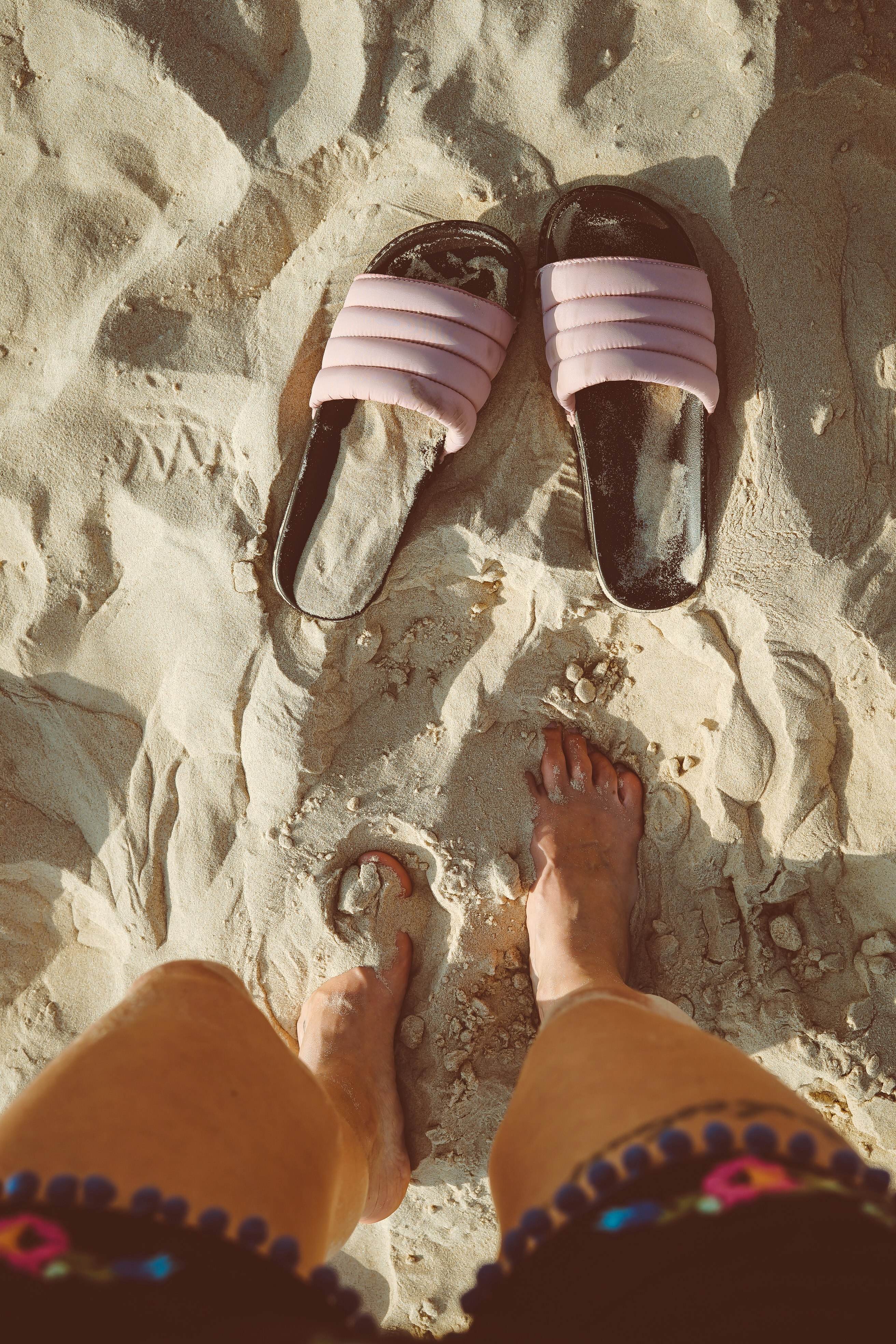 person standing on sand in front slide sandals