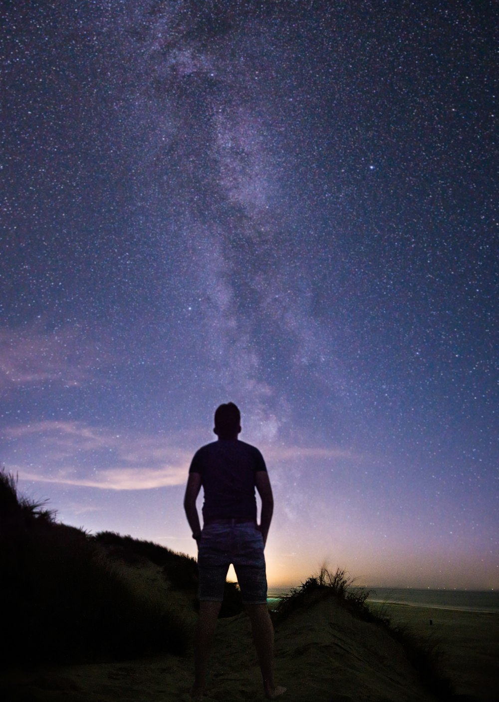 persona parada frente al rastro estelar de la Vía Láctea