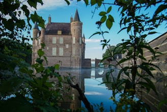 A serene view of Spøttrup Castle reflected in its surrounding moat under a soft morning light.