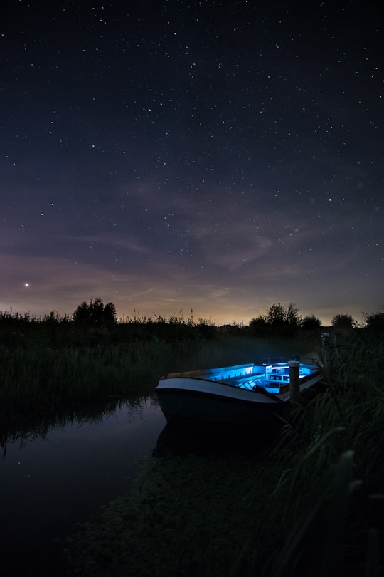 blue and white boat on river between trees at night in The Kilsdonk Mill Netherlands