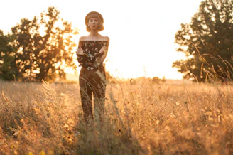 A model wearing a cozy, earth-toned t-shirt standing in a sunlit field of tall grass