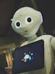 white robot toy holding black tablet
