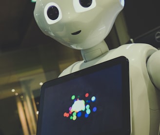 white robot toy holding black tablet