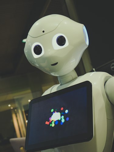 An elderly person sitting beside a small companion robot in a cozy home setting