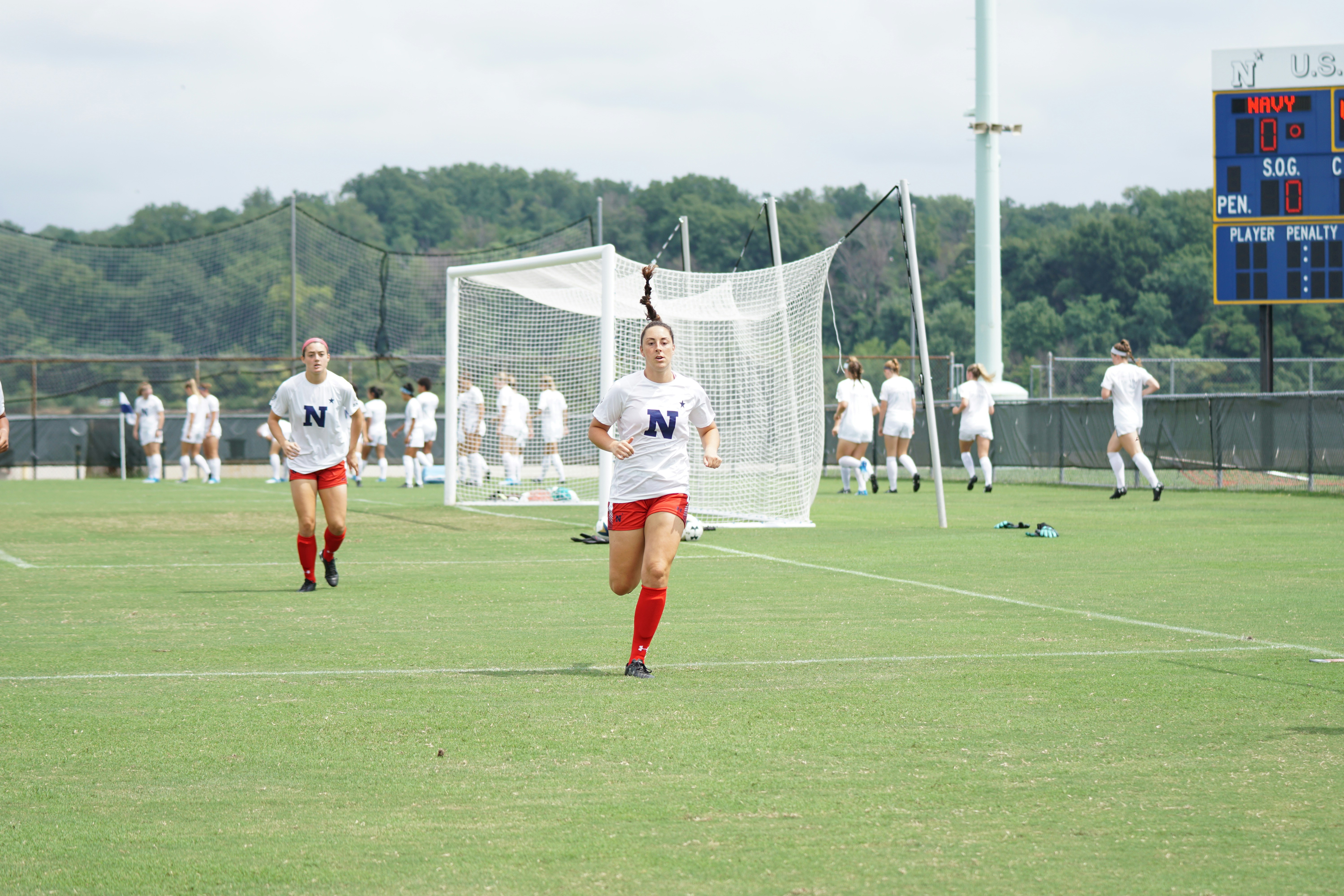 Female soccer players on a field practice drills, highlighting athletic perseverance amidst challenges like the pink tax.