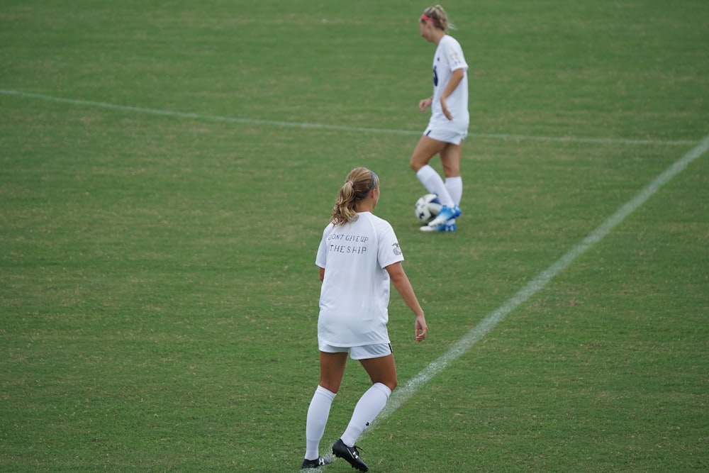 two woman football players on green football field