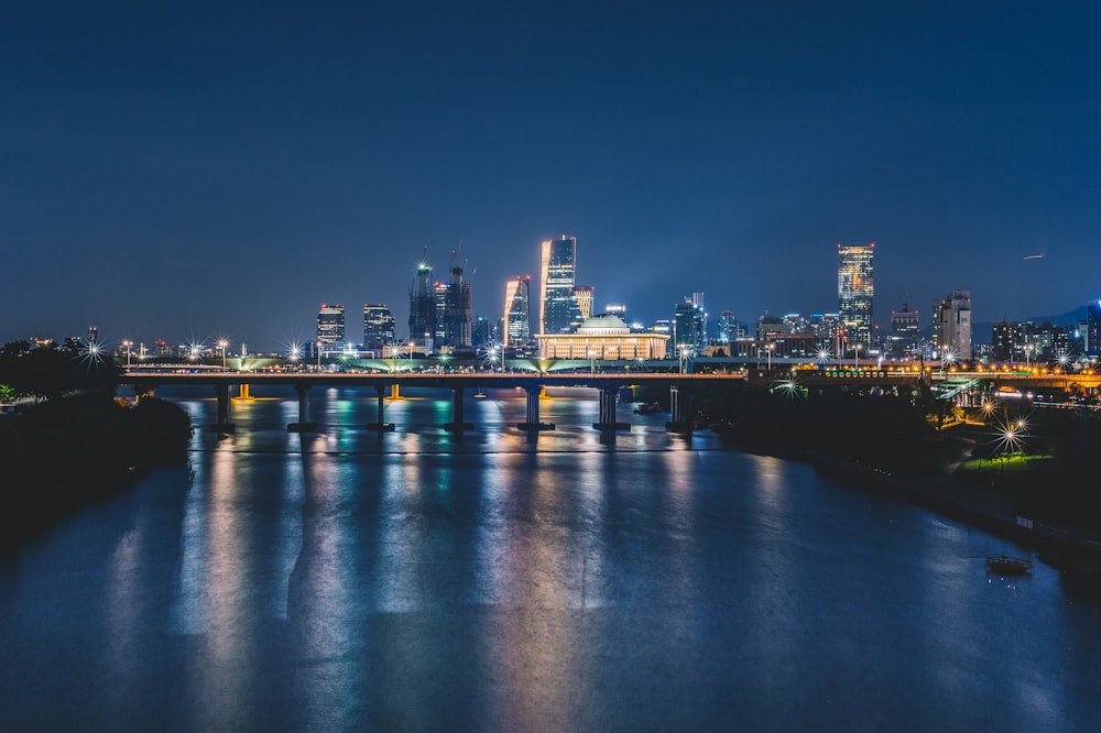 body of water near bridge and building at nighttime