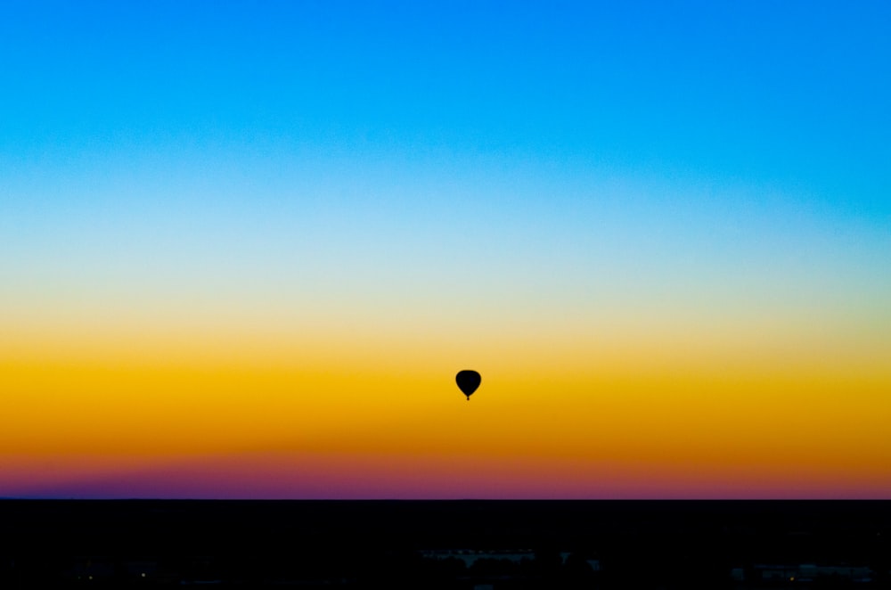 silhouette of hot air balloon under blue sky