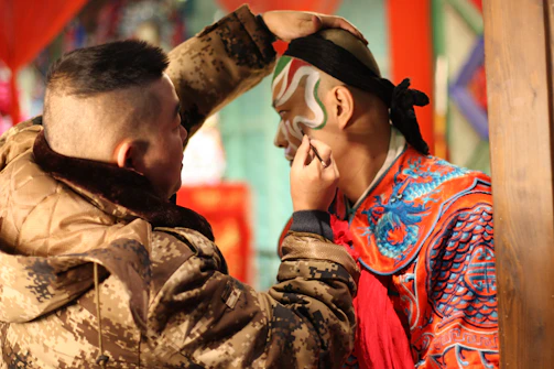 An artist painting a bride's face during a wedding celebration outdoors.