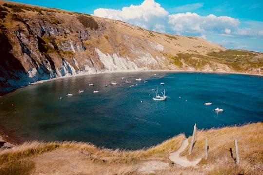white boats on lake near mountain at daytime in Lulworth Cove United Kingdom