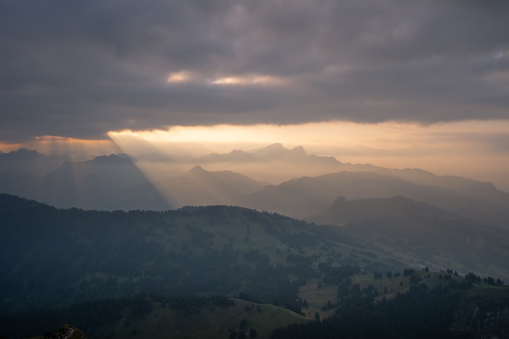 the sun is shining through the clouds over the mountains