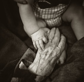 an older woman holding a baby's hand