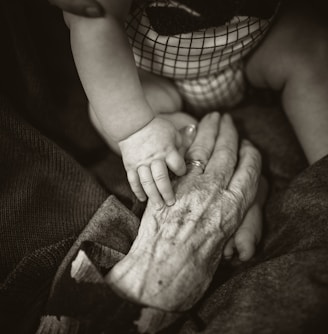 an older woman holding a baby's hand