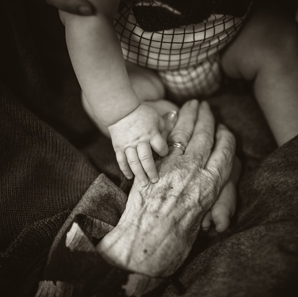 an older woman holding a baby's hand
