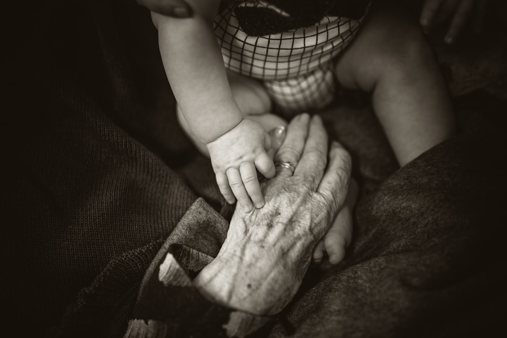 Eine ältere Frau, die die Hand eines Babys hält