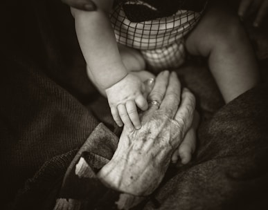 an older woman holding a baby's hand