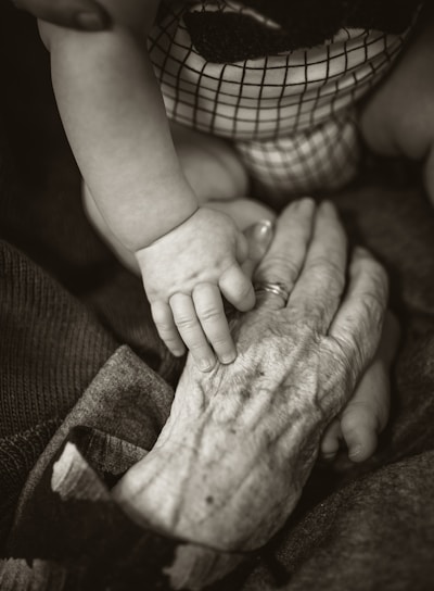 an older woman holding a baby's hand