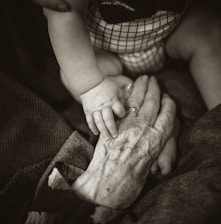 an older woman holding a baby's hand