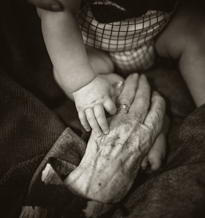 an older woman holding a baby's hand