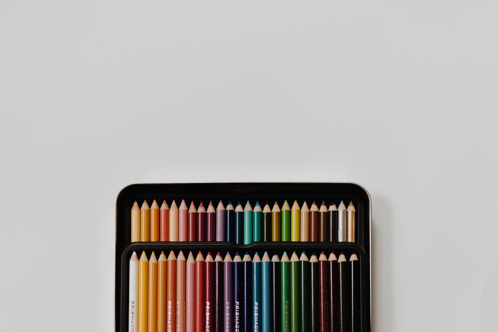 Set di matite di colori assortiti con astuccio su superficie bianca