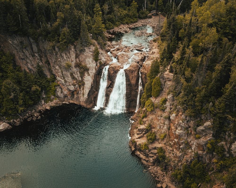 aerial view photography of waterfalls surrounded by pine trees