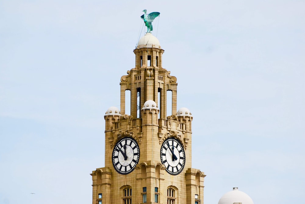 Edificio de hormigón beige con dos relojes bajo cielo azul nublado