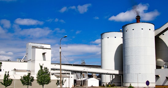 Technicians carefully assembling a large silo structure under a clear blue sky.