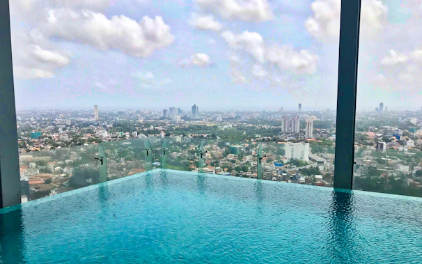 A rooftop pool overlooking a bustling city skyline under a clear blue sky.