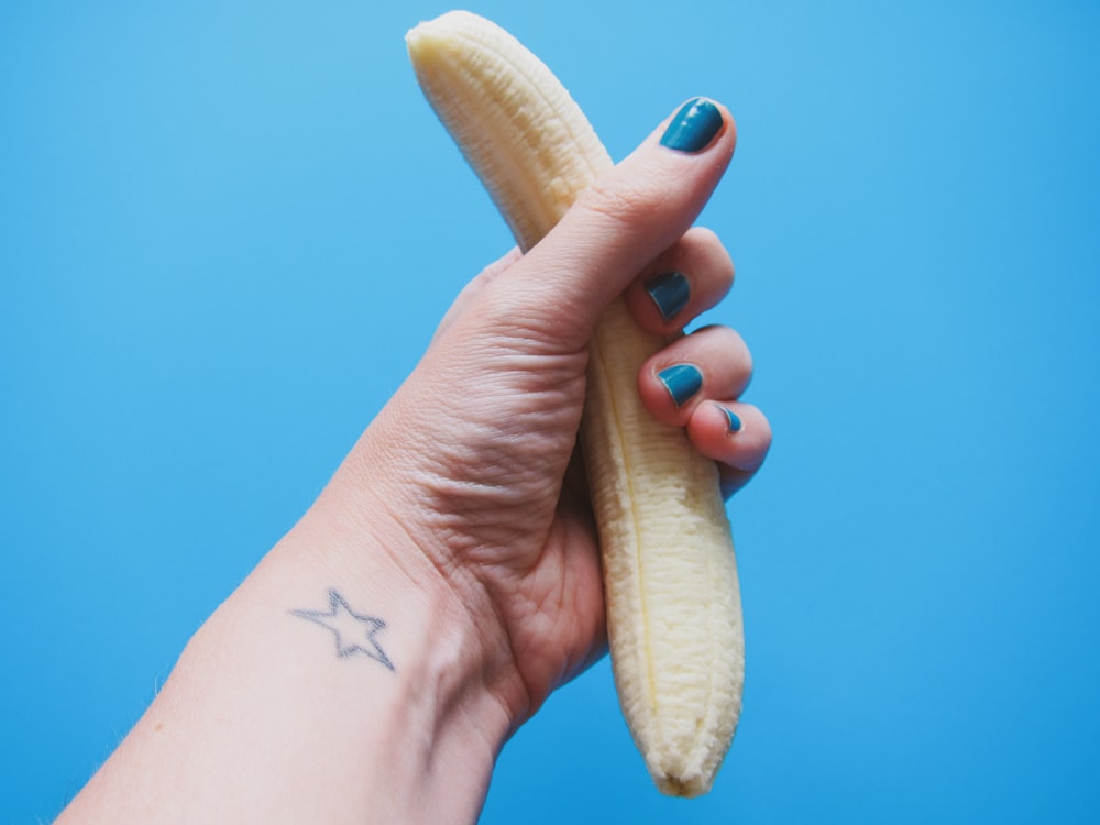 persona sosteniendo una fruta de plátano pelada