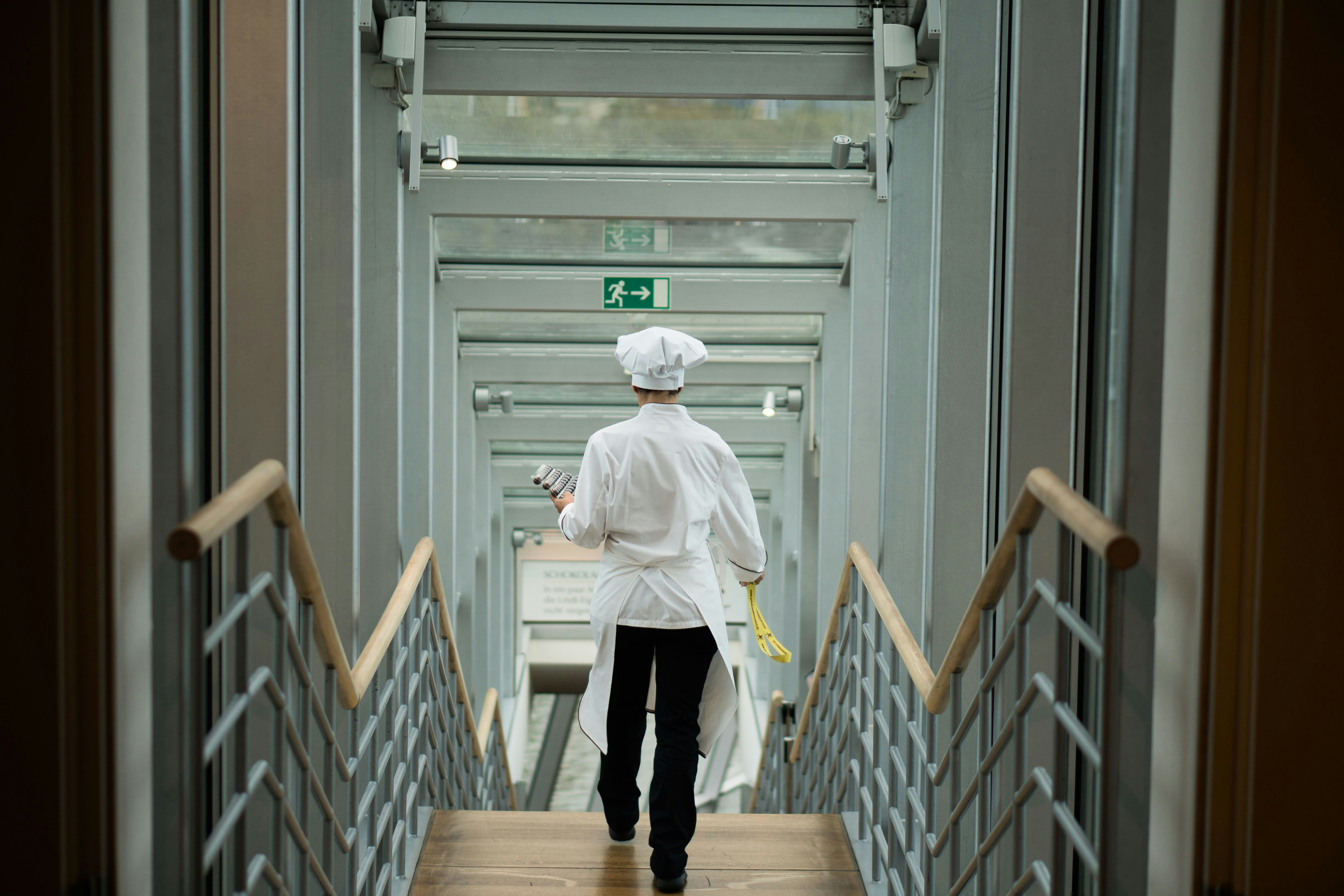 person wearing white apron walkin on stairs